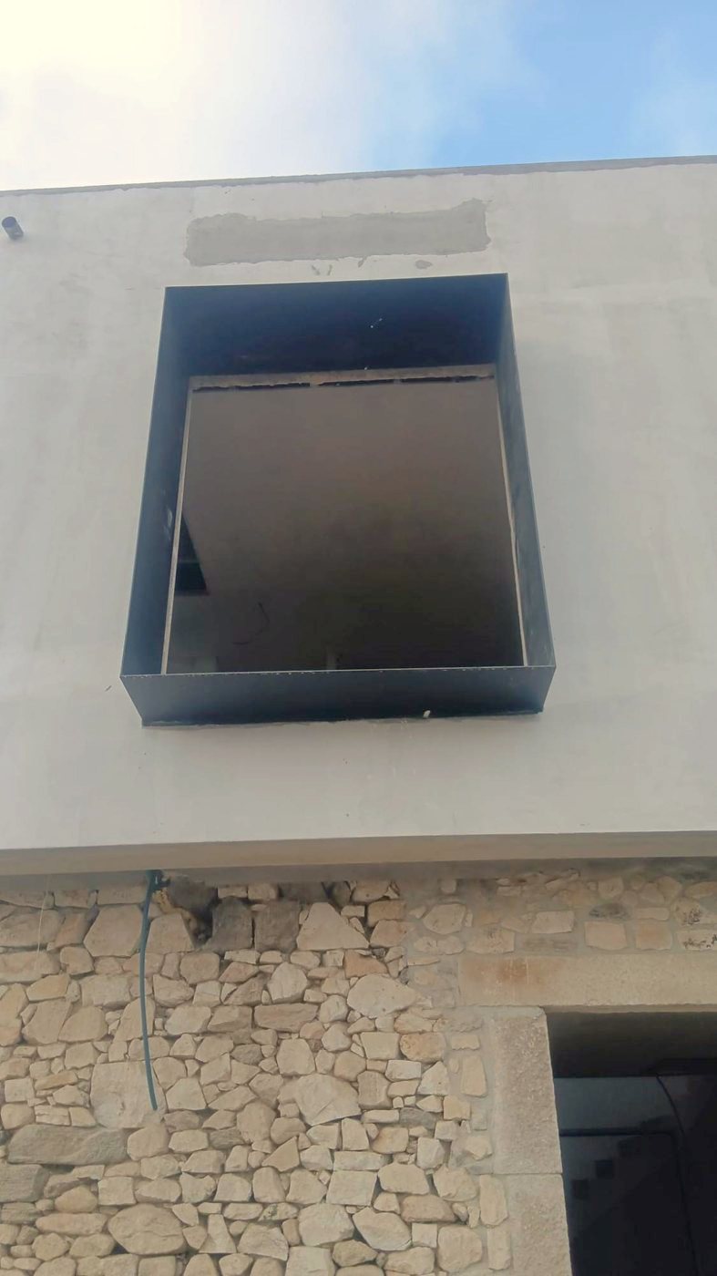 Steel window frame above a stone wall